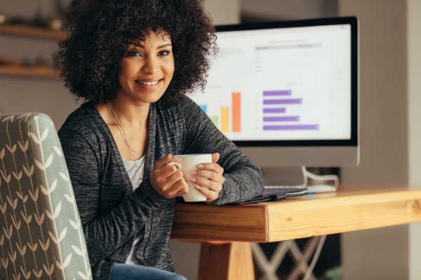 Woman sitting at computer with coffee in hand